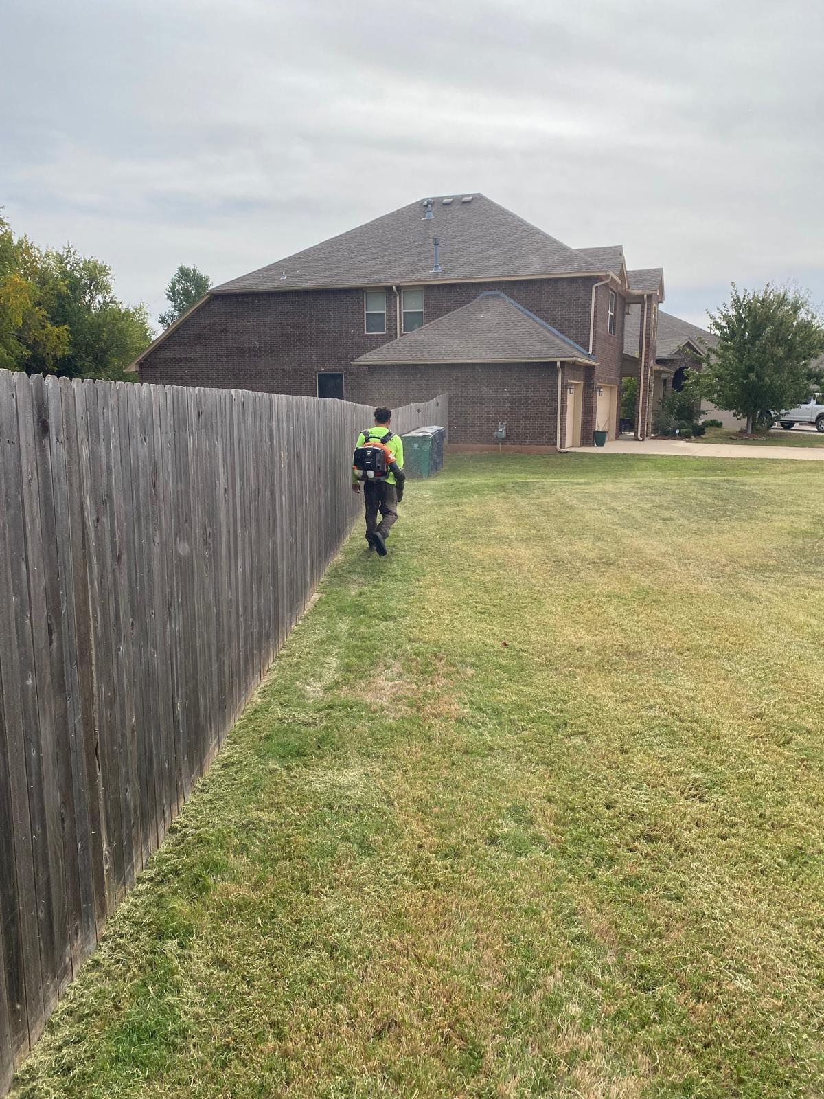 Tech blowing leaves off walkways and beds