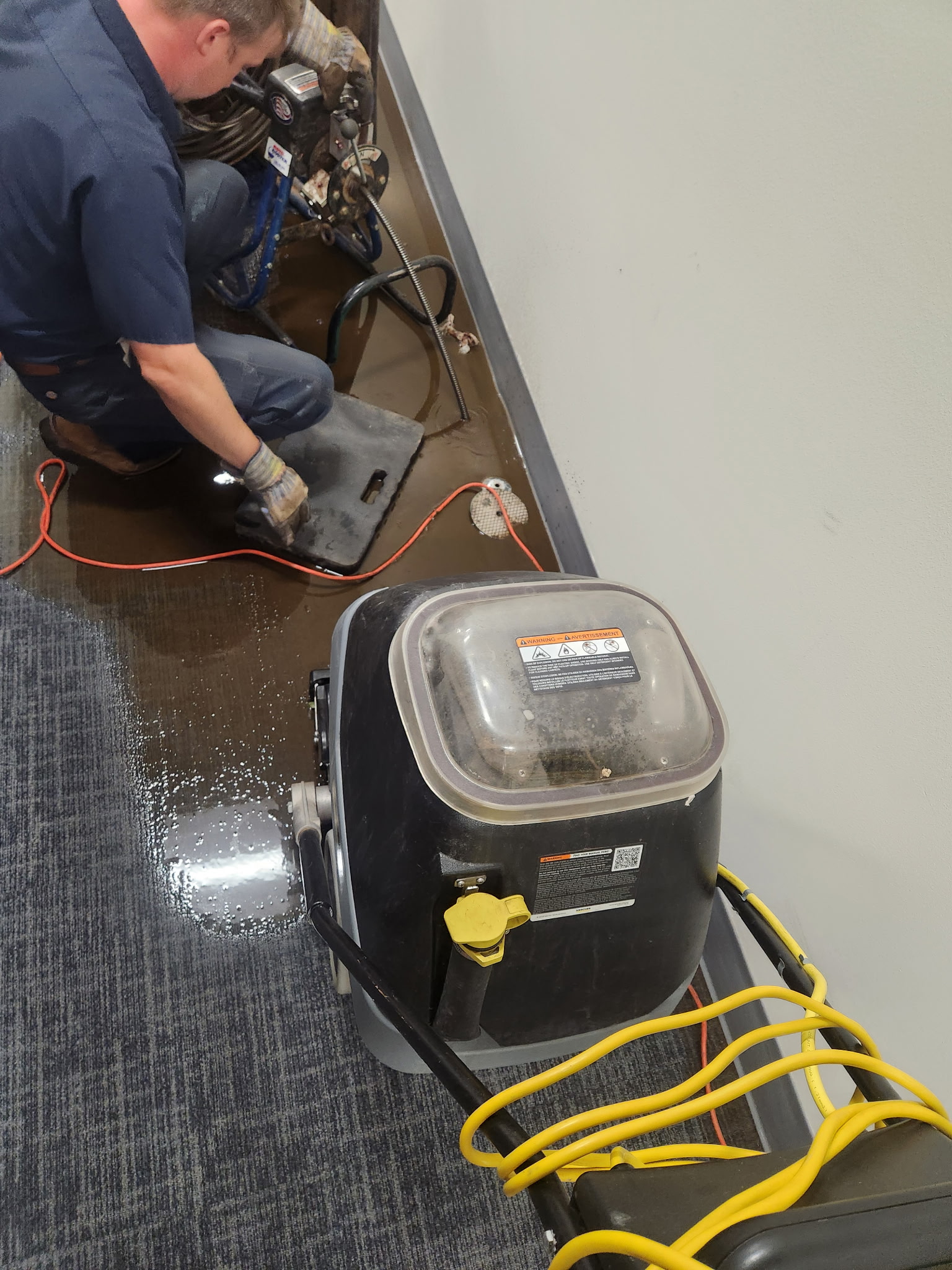 Wet vac extracting water near a floor drain